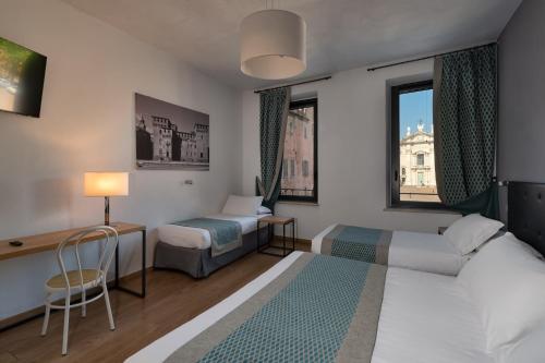 a hotel room with a bed and a desk and a bed and window at Hotel dei Gonzaga in Mantova