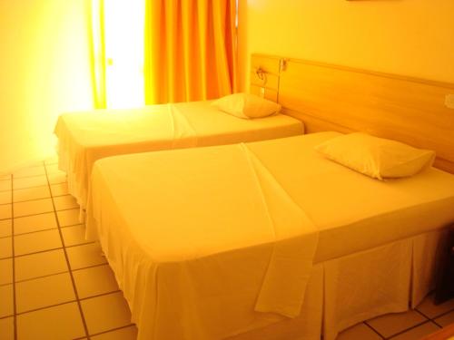 two beds in a hotel room with white sheets at Rede Andrade Aracaju in Aracaju