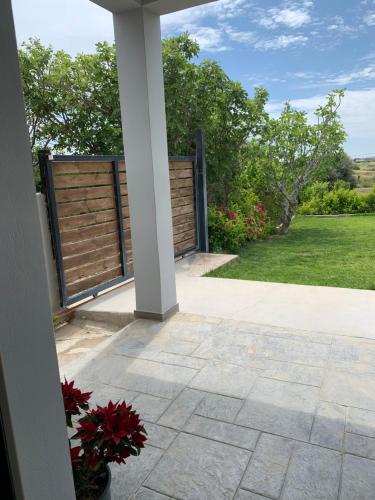 a porch with a fence and flowers in a yard at Elena villa-apartments in Asklipiḯon