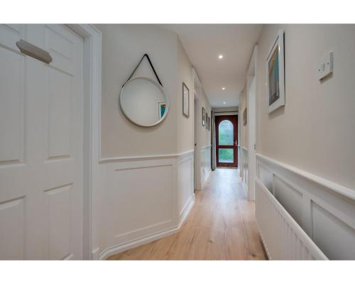 a hallway with white walls and a mirror on the wall at Central Belfast Apartments Windsor in Belfast