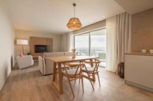 a dining room and living room with a table and chairs at Aqualuz Troia Mar by The Editory in Troia