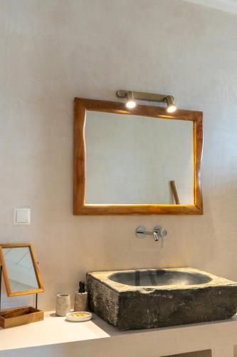 a bathroom with a stone sink and a mirror at Heliopetra Punta in Ios Chora