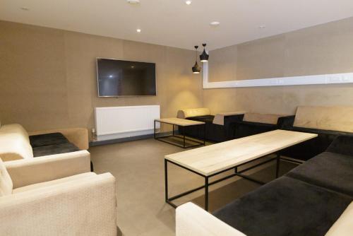 a living room with couches and tables and a tv at For Students Only Cosy Ensuites at New Cross in London in London