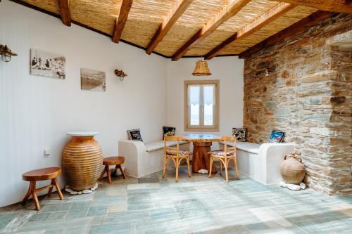 Habitación con mesa, sillas y pared de piedra. en Heliopetra Punta, en Ios Chora