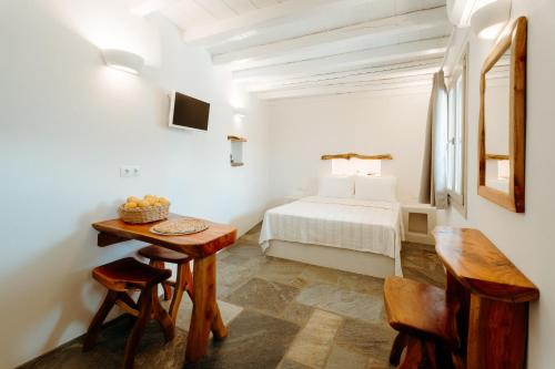 1 dormitorio con 1 cama, mesa y sillas en Heliopetra Punta, en Ios Chora