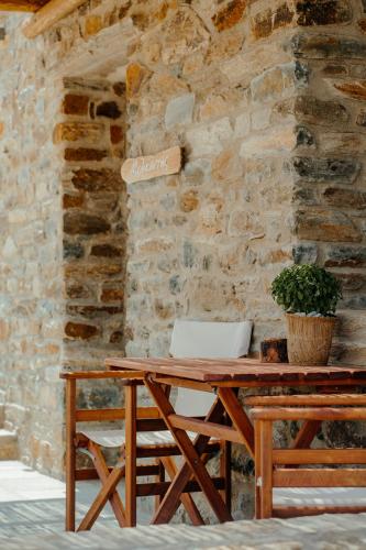 a wooden table with a laptop on a stone wall at Heliopetra Punta in Ios Chora