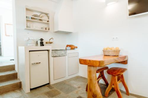 a small kitchen with a wooden table and stool at Heliopetra Punta in Ios Chora