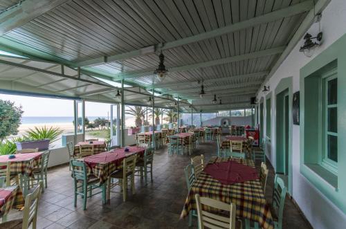 a restaurant with tables and chairs with the ocean in the background at Psili Ammos Studios in Aliko Beach