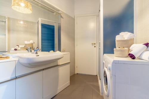 a white bathroom with a sink and a washing machine at La Casa di Madi in Riomaggiore
