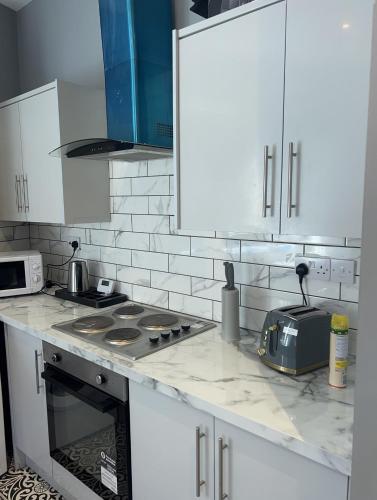 a kitchen with white cabinets and a stove top oven at City West Apartments 3 bedroom large & modern Apartment in Newcastle upon Tyne