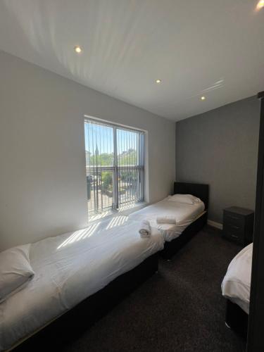 a bedroom with two beds and a large window at City West Apartments 3 bedroom large & modern Apartment in Newcastle upon Tyne