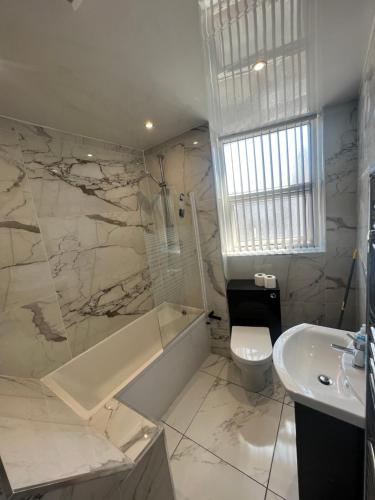 a bathroom with a tub and a toilet and a sink at City West Apartments 3 bedroom large & modern Apartment in Newcastle upon Tyne