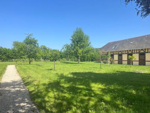 un champ herbeux avec un bâtiment en arrière-plan dans l'établissement Le Gîte du Verger au cœur des boucles de Seine, à Yville-sur-Seine