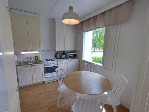 cocina con mesa, sillas y ventana en Asuntos-2, en Lahti