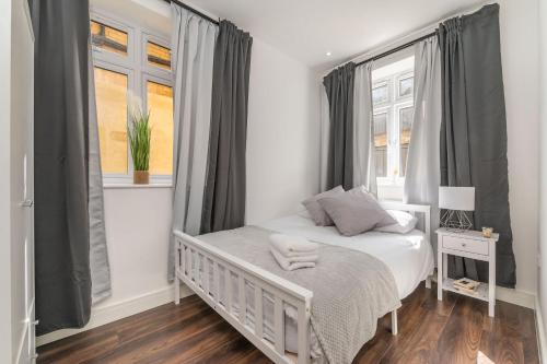 a bedroom with a white bed and two windows at Luxury Apartment near Central London in London