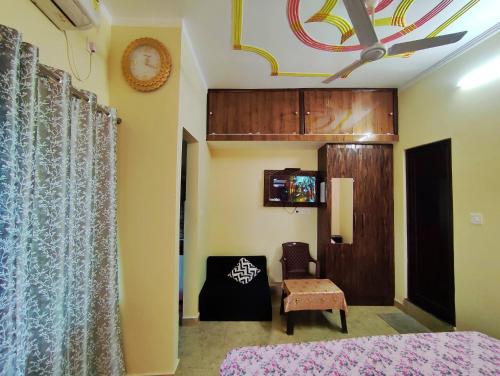 a bedroom with a bed and a chair and a clock at Anandam Home Stay in Rishīkesh