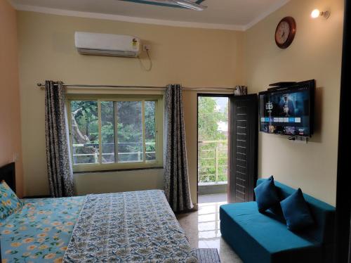 a bedroom with a bed and a tv and a couch at Anandam Home Stay in Rishīkesh