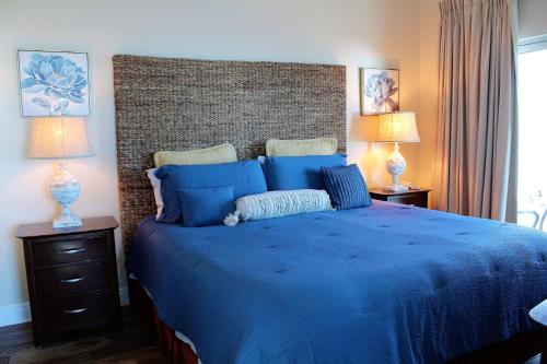a bedroom with a large blue bed with two lamps at Crystal Tower 1509 by ALBVR - Luxurious 15th Floor Condo with Breathtaking Views in Gulf Shores