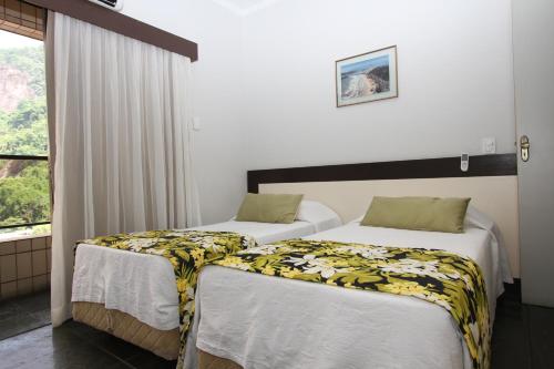 two beds in a room with a window at Flat Itararé Tower Beach in São Vicente