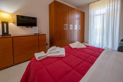 a bedroom with a red bed with a dresser and a tv at Villa Floyd Charming Rooms B&B in Pachino