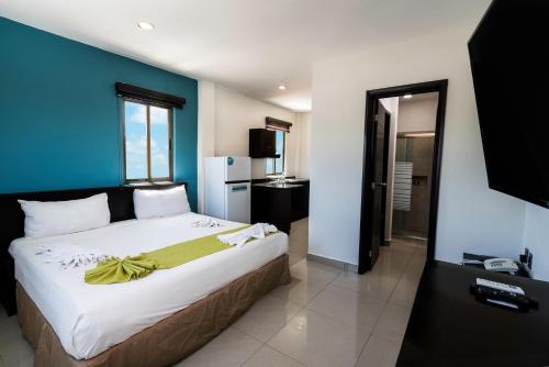 1 dormitorio con 1 cama grande y pared azul en Hotel Ambra, en Playa del Carmen