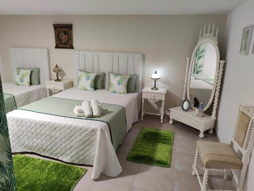 a white bedroom with two beds and a mirror at HOUSEMARIA in Nazaré