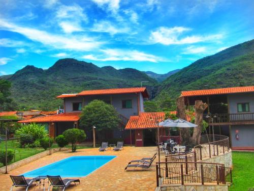 a resort with a pool and mountains in the background at Pousada Mandalla in Serra do Cipo