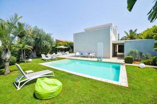 een zwembad in een tuin met stoelen en een huis bij Villa Ponente - Design House with Private Pool in Marina di Ragusa