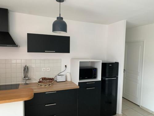 a kitchen with black cabinets and a black refrigerator at Nouveauté Sunset appart vue exceptionelle in Saint-Denis