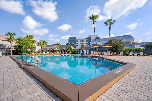 a swimming pool at a resort with tables and umbrellas at Holiday Inn Orlando International Drive - ICON Park in Orlando