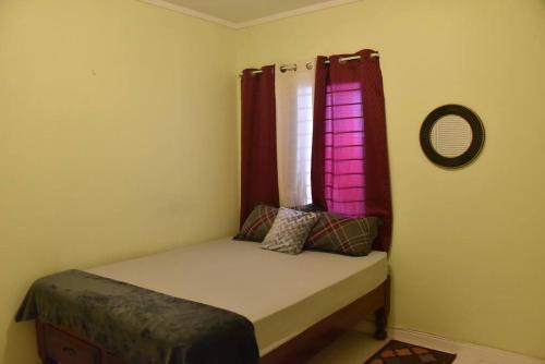 Cama pequeña en habitación con ventana en Cozy and Secure Jacaranda Home, en Spanish Town