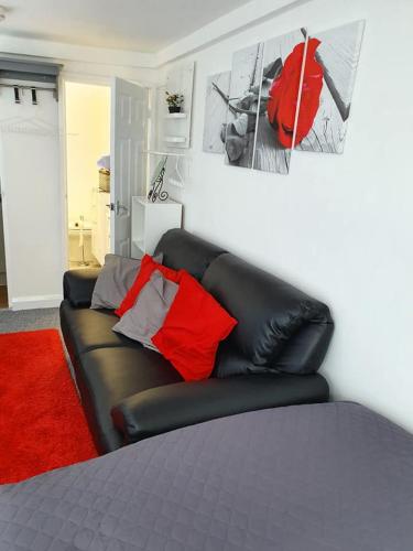 un sofá de cuero negro con almohadas rojas en una habitación en Richfieldsat59 en Milton Keynes