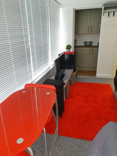 a living room with a red rug and a red chair at Richfieldsat59 in Milton Keynes