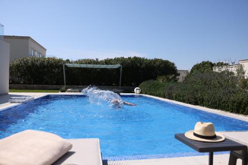 a swimming pool with a fountain in the middle at Lusso Mare Istria Luxury Beach villa in Savudrija