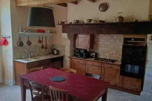 a kitchen with a red table and a kitchen with a stove at Maison de maître avec piscine in Lombers