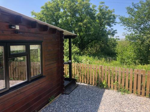 a log cabin with a fence next to it at Cotts Cabin - Welcombe - 2 min walk to pub in Bideford