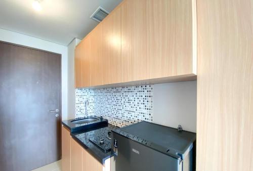 eine Küche mit einer Spüle und einem schwarzen Kühlschrank in der Unterkunft Apartemen Transpark Juanda Bekasi by Cheapinn in Padurenan