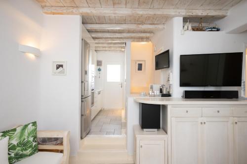 a kitchen and living room with white cabinets and a flat screen tv at Blue, White and Grey Suites in Ornos