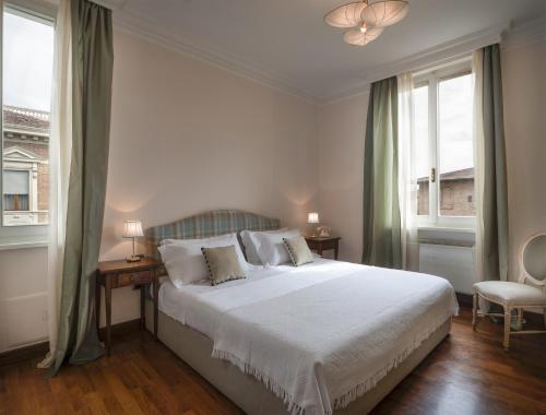 1 dormitorio con 1 cama blanca grande y 2 ventanas en La Villa, en Siena