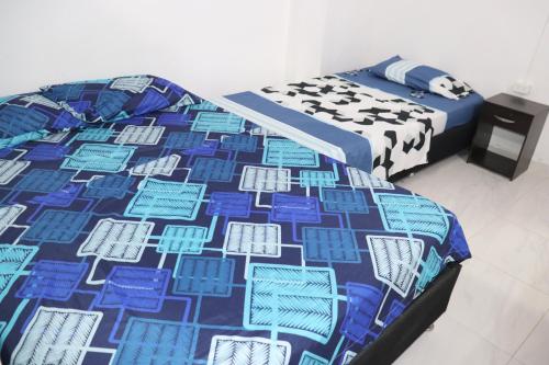 um quarto com 2 camas com uma colcha azul e branca em RIO Colors - Hospedaje em Barrancabermeja