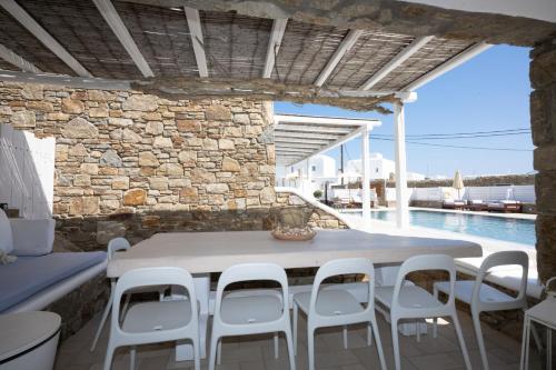 a stone walled patio with a white table and chairs at Blue, White and Grey Suites in Ornos