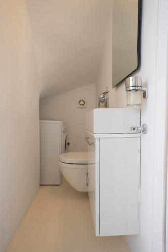 a white bathroom with a toilet and a sink at Blue, White and Grey Suites in Ornos