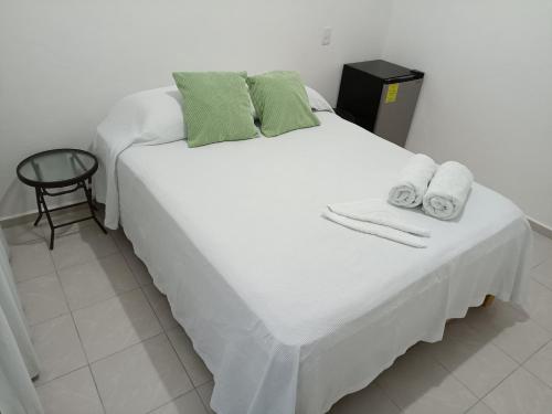 Una gran cama blanca con toallas encima. en Casa Tauch en Cancún