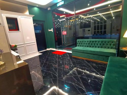 a room with a green couch and a table at 1 Day Car Hotel - BG Perdana in Batu Gajah