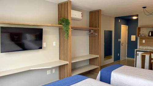 a hotel room with two beds and a tv and shelves at Costa Solar Lagoa in Florianópolis