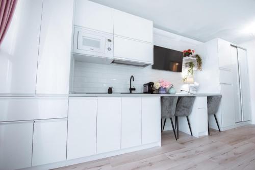 a white kitchen with white cabinets and a table at Studio Vladut in Saturn