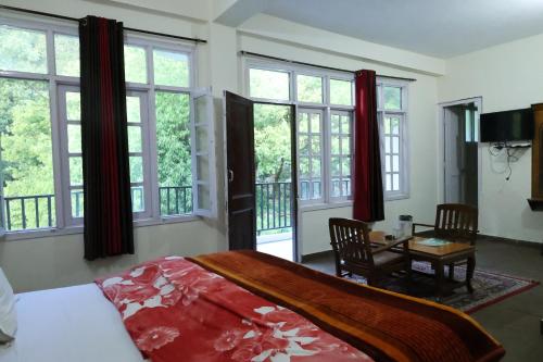 a bedroom with a bed and a table and windows at Paradise Guest House Dalhousie- Near Panchpula Water Fall in Dalhousie
