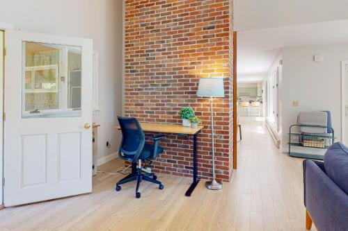 a living room with a brick wall and a desk at Casco Breeze in North Harpswell