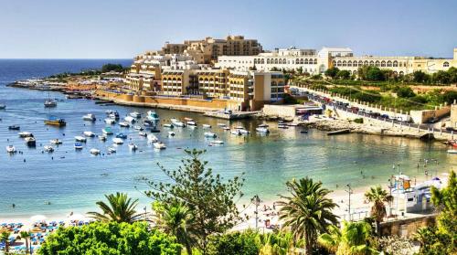 a beach with boats in the water and buildings at Holiday - Malta Balluta Beach in Sliema