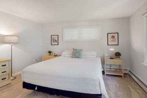 a bedroom with a large white bed and two tables at Casco Breeze in North Harpswell